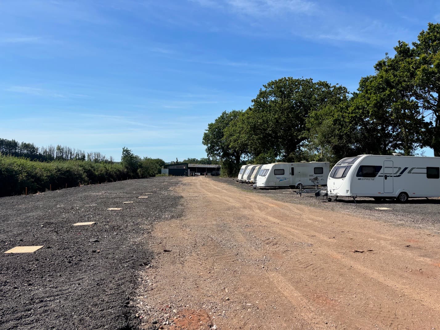 Storage site under a clear blue sky, oak trees at the perimeter